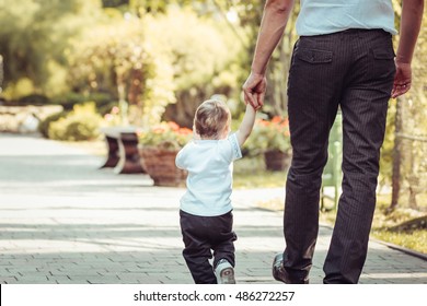 Rear view of father and son holding hands while walking