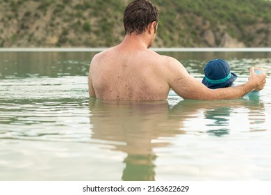 Rear View Of A Father Teaching To Swim To Her Little Daughter In A Natural Lake. Summer Activities.