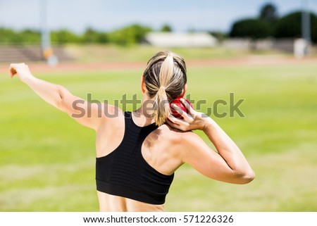 Rear view of female athlete preparing to throw shot put ball in stadium