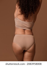 Rear view of female body with flaws and imperfections isolated on beige background with copy ad space. Body positivity, love to your body, self-confidence and the concept of self-acceptance