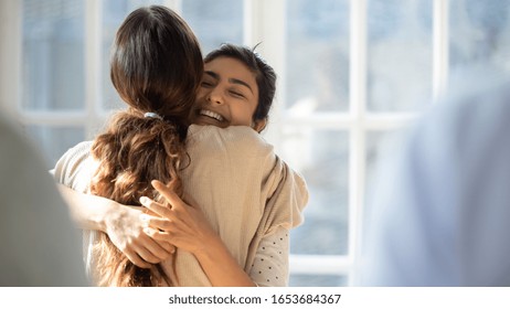 Rear view female cuddle Indian best friend glad to see each other enjoy tender moment show friendly relation and affection, woman psychologist counsellor hug girl supports her at group therapy session - Powered by Shutterstock