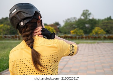 Rear view of female cyclist having neck pain from riding a bike long time. Poor posture is a major contributor to neck pain whilst cycling.