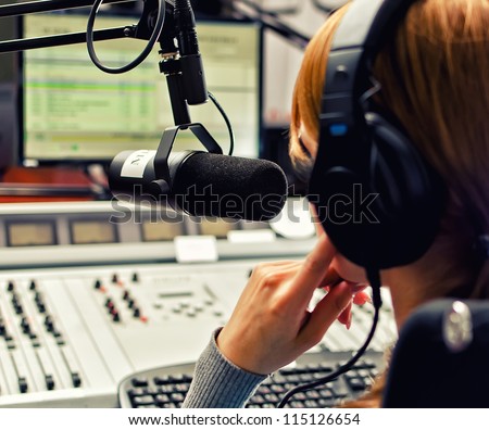 Rear view of female dj working in front of a microphone on the radio