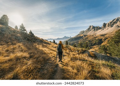 Rear view of Female hiker trekking on hiking trail in Massif Des Cerces of Claree Valley during autumn at French Alps, France - Powered by Shutterstock