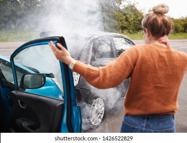 Rear View Of Female Motorist With Head Injury Getting Out Of Car After Crash