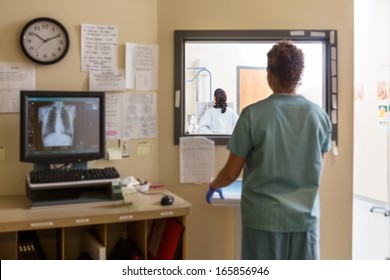 Rear view of female nurse operating machine in xray control room - Powered by Shutterstock