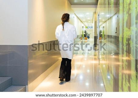 Rear view of a female ophthalmologist walking along a corridor in the clinic