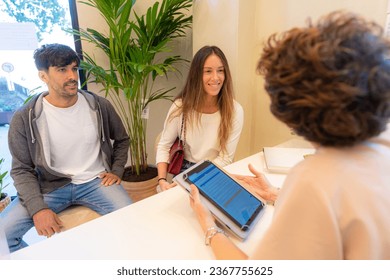 Rear view of a female receptionist using digital tablet to attend two patients - Powered by Shutterstock