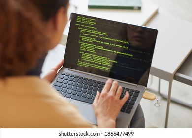 Rear view of female software programmer typing codes on laptop working with new software