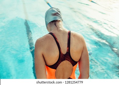 Rear view of female swimmer about start swim. Woman in swimwear practising in pool. - Powered by Shutterstock