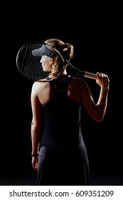 Rear View Of Female Tennis Player Holding Racket On Her Shoulder Looking At Distance Isolated On Black