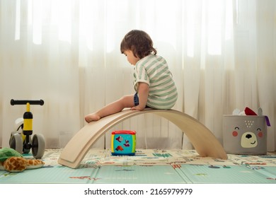 Rear View Of A Female Toddler Playing With A Balance Board At A Montessori Playroom.