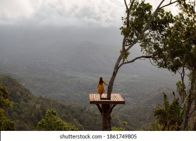 Rear view female tourist enjoying nature looking at the mountains and Agug volcano while standing on photo spot on the tree