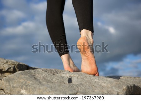 Rear view of female walking on rock barefoot 