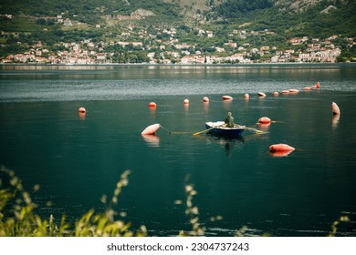 Rear view of a fisherman fishing in a boat in the serene waters of Boka Bay, Montenegro