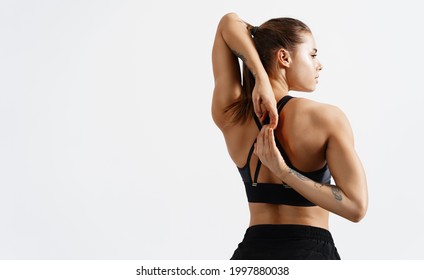 Rear view of fit and sporty fitness woman stretching arms and back before workout exercises. Woman back in black sport clothing standing on white background, training concept - Powered by Shutterstock