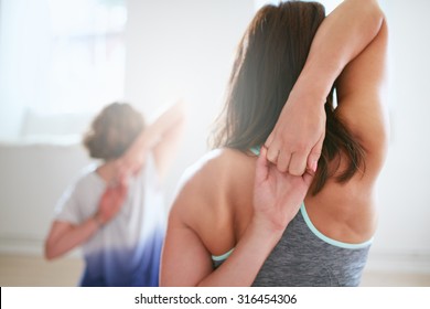 Rear view of fit woman doing gomukhasana in yoga class. Fitness female holding hands behind their back and stretching. Triceps and shoulders workout. - Powered by Shutterstock