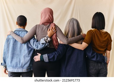 Rear view of four women with arms around each other in support of International Women's Day - Shutterstock ID 2123691773