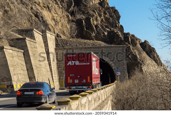 Rear view of freight truck on the mountain road, at\
the entrance to the tunnel. Truck belonging to the Slovak company\
ATO TRANS. Import and export of goods concept. Orsova, Romania,\
October 15, 2021