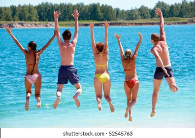 Rear View Of Friends Jumping Into Water During Summer Vacation