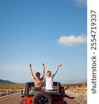 Rear View Of Friends On Road Trip Driving Convertible Car On Country Road With Women Sitting In Back