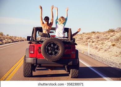 Rear View Of Friends On Road Trip Driving In Convertible Car