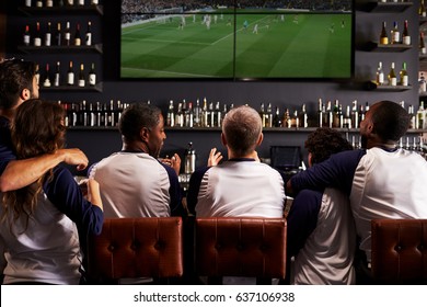 Rear View Of Friends Watching Game In Sports Bar Celebrating