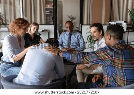Rear view frustrated depressed man feeling unhappy thinking about problems during group counseling session with psychologist, diverse people sitting in circle, helping patient touching shoulder