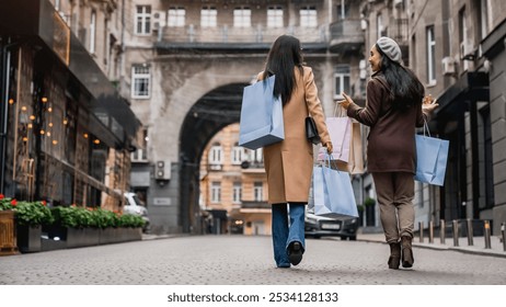 Rear view full length shot of female friends out for shopping in the city. Two girlfriends walking together with bags, buying clothes on black friday. - Powered by Shutterstock