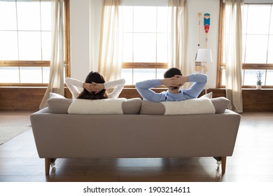 Rear View Full Length Young Couple Relaxing On Couch In Modern Apartment, Young Woman And Man Leaning Back With Hands Behind Head, Resting, Enjoying Lazy Weekend At Home, Moving Day Or Mortgage