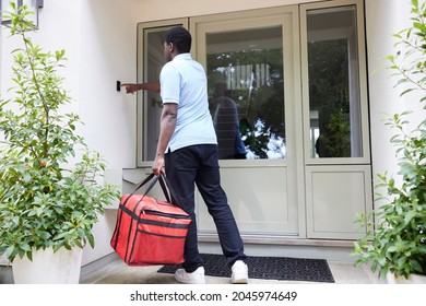 Rear View Of Gig Economy Driver Ringing Doorbell Delivering Online Takeaway Food Order To House