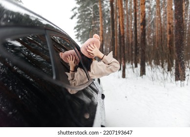 Rear view of girl in car over snowy forest on winter roadtrip