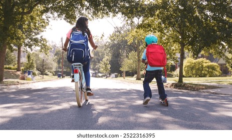 Rear View Of Girl Wearing Riding Bike And Boy Riding Scooter Along Suburban Street On Way To School - Powered by Shutterstock