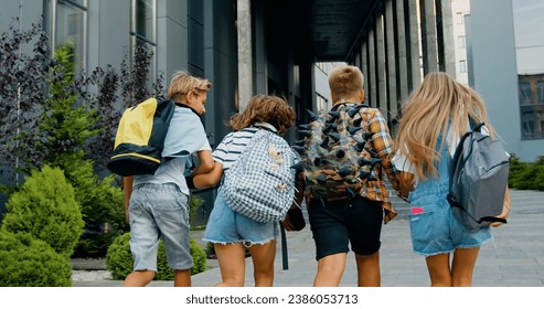 Rear view. Good-looking school child friends climb stairs going to class with backpacks. Boys and girls high school students having fun after school. They are smiling and having fun. - Powered by Shutterstock