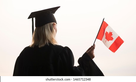 Rear View Of A Graduate With The Flag Of Canada In Hand. Study In Canada