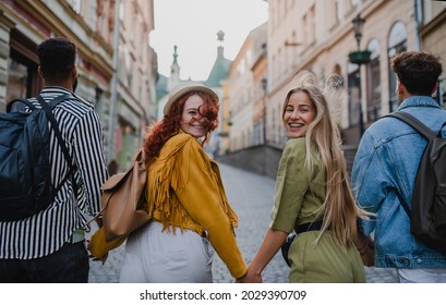 Rear View Of Group Of Happy Young People Outdoors On Trip In Town, Walking And Looking Back.