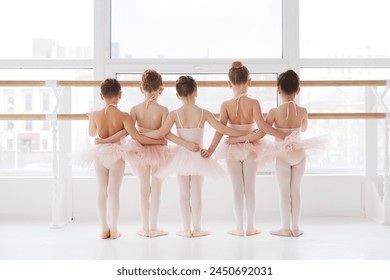 Rear view of group of little girls, ballet dancers in tutus preparing for ballet practice near window. Classical ballet school. Concept of art, sport, education, hobby, active lifestyle, leisure time. - Powered by Shutterstock