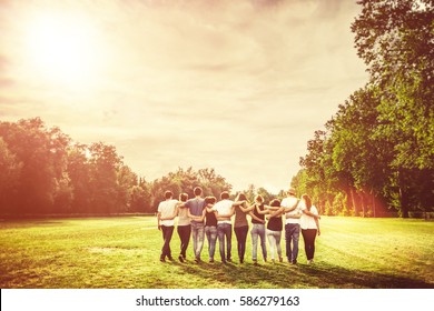 Rear view of group of Teenage Friends walking in the Park at Sunset - Powered by Shutterstock