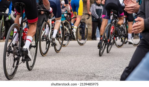 Rear View Of A Group Of Unrecognizable Road Cyclists In Full Physical Effort With Cheering Public. Male Athlete Cycling Outdoors.