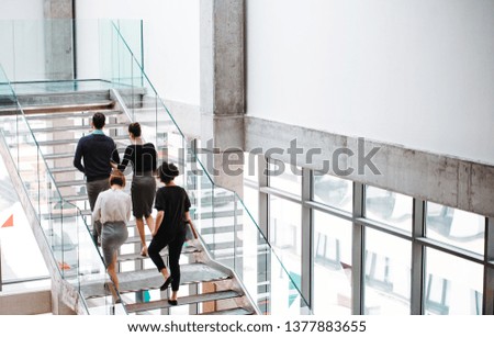 Rear view of group of young businesspeople walking up the stairs.