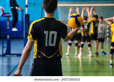 Rear view of guy in black yellow sportswear uniform with 10 number at active match. Team volleyball game, volleyball court in sport school gym. Sports games, team success concept. Copy ad text space - Powered by Shutterstock