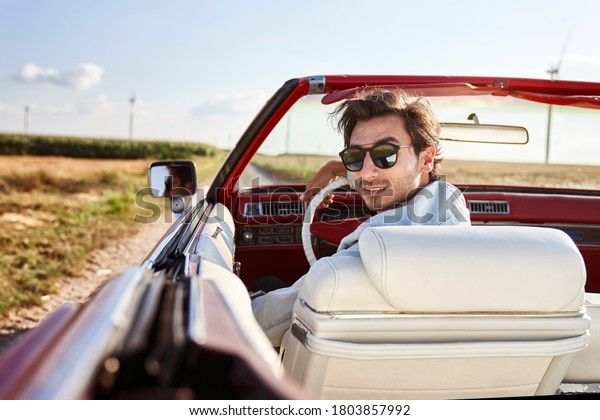 Rear view of handsome man in a red convertible      \
                        