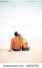 Rear view of happy couple sitting together on sand