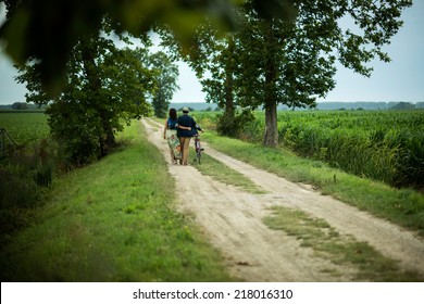 Rear View Of A Happy Couple Walking Holding Bike