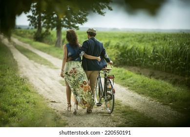 Rear view of a happy couple walking holding bike
