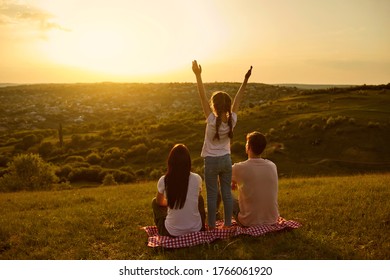 Rear view of a happy family resting looking at a beautiful sunset in the evening on nature. - Powered by Shutterstock