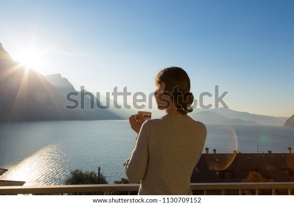 海の湖や山々の自然の風景を眺めながら美しい穏やかな朝を楽しむ 幸せな自由な女性の背景が コーヒーを飲みながら新しい日に始まる イタリア ロンバルディア リバディソルト の写真素材 今すぐ編集