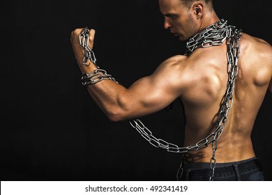 Rear view of healthy muscular young man with chain at his neck and strong arms. Black background.  Fitness concept - Powered by Shutterstock