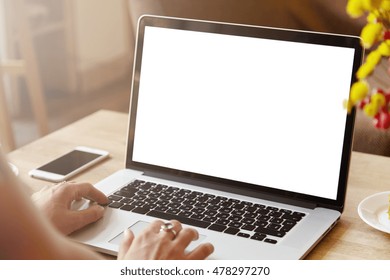 Rear View Of High School Girl Using Laptop For Doing Homework, Browsing Internet, Searching For Required Information, Sitting At Desk With Mobile Phone With Copy Space Screen Lying Next To Her