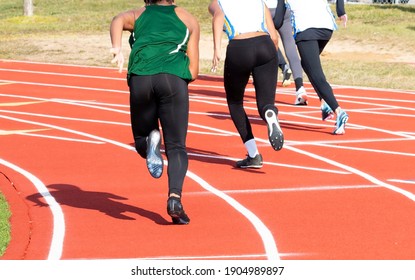 Rear View Of High School Girls Starting A Sprint Race On On Outdoor Track In The Winter.